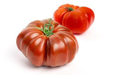 Two dark red heirloom tomatoes with distinctive wrinkles and creases isolated on white