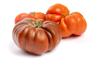 Multi colored red heirloom tomatoes with distinctive wrinkles and creases and irregular shape isolated on white