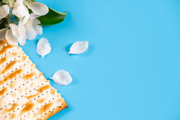 Holiday passover flatlay. Traditional matzah bread and spring flowers on blue background.