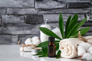 Essential oil, towel and candles on gray stone background. Spa wellness accessories and cosmetics.