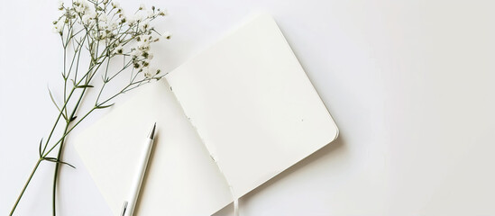 Blank, white notepad, pen and flowers on the table
