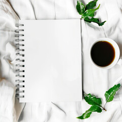 Blank notepad and cup of coffee on white cloth
