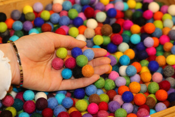 hand of a young girl with many balls made of boiled wool for sale in the hobby shop