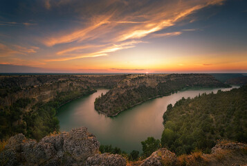 Sunset at the edge of the cliff in the Hoces del Rio Duraton Natural Park, Segovia, with the clouds dyed in warm colors