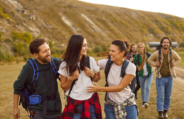 Candid shot of happy friends having fun on a hiking tour. Group of young people with backpacks...