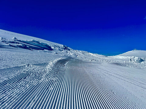 Perfect Run: Skiing on Corduroy Slopes Against a Dark Blue Sky