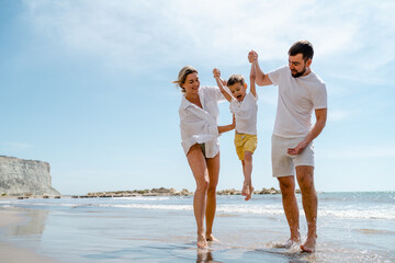 Happy family enjoys a playful walk along the sea on a Mediterranean beach