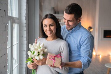 Shot of cheerful young caucasian man that giving present box to his wife with look on her....