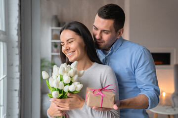Close up shot of cheerful young caucasian man that giving present box to his wife with look on her....