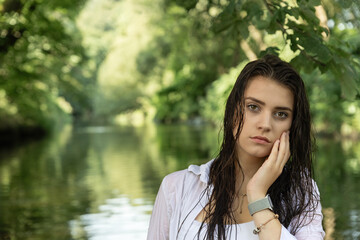 Portrait of a young brunette with wet hair holding her face. Horizontally. 
