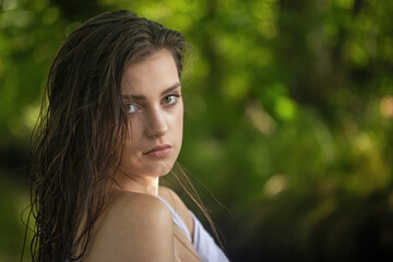 Portrait of cool girl with wet hair looking at camera over bare shoulder. Horizontally. 