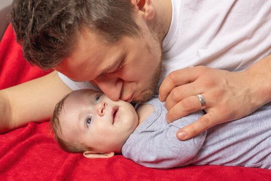 Young father is kissnig his newborn baby boy. Horizontally. 