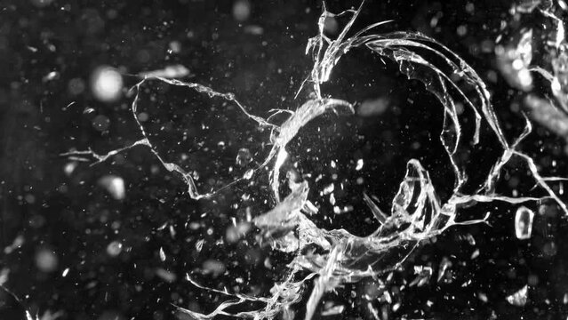 Super slow motion of gunshot through the glass, shattering against black background . Filmed on high speed cinema camera, 1000 fps.