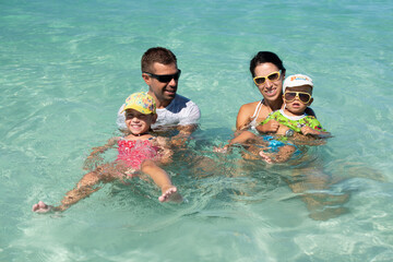 mom and dad with children, playing with kids, family on the beach, swimming in the ocean, vacations...