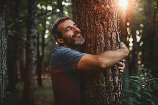 Smiling man hugging a tree in nature