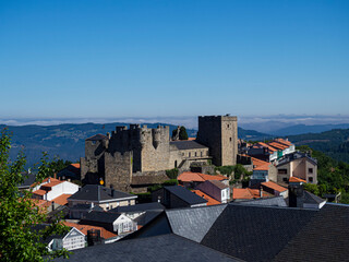 Vista de lejos del castillo de Castrocaldelas , pueblo de Orense con tejados rojos y negros sobre...