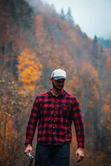 Handsome Lumberjack in Red Checkered Shirt with Axe in Autumn Foggy Forest - 785649141