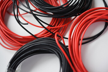 Wires for electronics on a white background. Two coils of red and black wires.