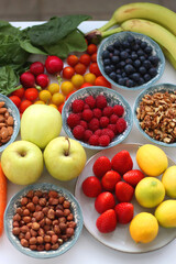 Apples, lemons, bananas, berries, carrots, leek, tomatoes, radishes, spinach and various nuts on white background. Healthy seasonal fruit and vegetable. Selective focus.
