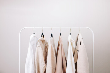 Wardrobe essentials of white and beige colors, stylish woman's closing on the rack