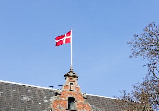 Danish flag on the roof of a building against a blue sky.