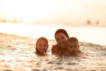 mother with children, playing with kids, family on the beach, swimming in the ocean, vacations in...