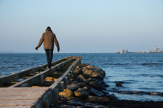 Mann balanciert auf Steg im Winter.