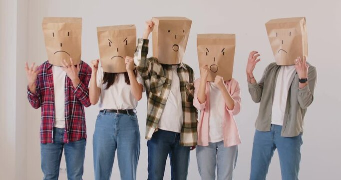 Group of faceless people standing in a row on gray background with paper bag on head with drawn different emotions fighting for human rights on demonstration. Protest concept. 4k video.