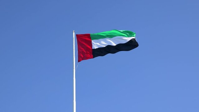 UAE flag waving in the blue sky, national symbol of UAE