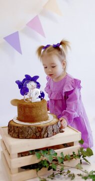 Cute little girl celebrate Happy Birthday and licks lollipops on a sweet cake