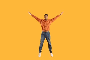 Fototapeta na wymiar Excited man jumping with joy against yellow background