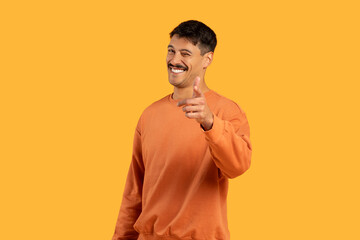 Man in orange sweater pointing at camera isolated
