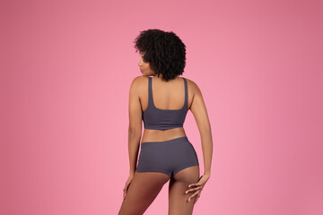 Sporty African American lady posing isolated on pink background