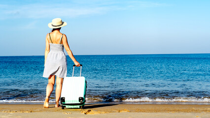 A girl on the beach with a suitcase meets a plane