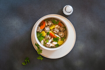 White bean beef meatball soup with  seasonal vegetables on grey background, directly abiove - 785666387