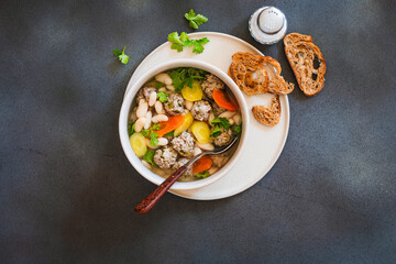 White bean beef meatball soup with  seasonal vegetables on grey background, directly abiove - 785666397