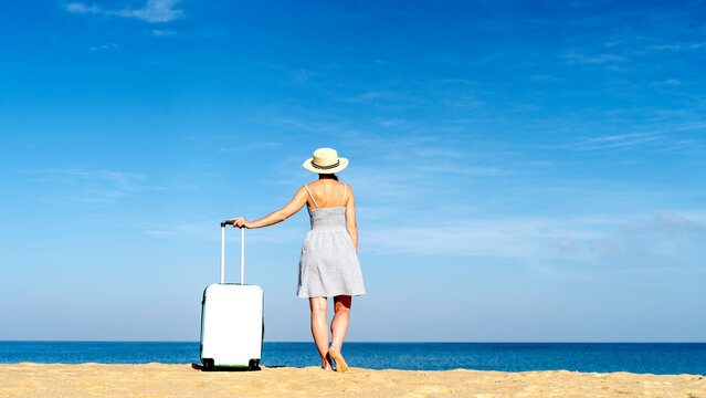 A girl on the beach with a suitcase meets a plane