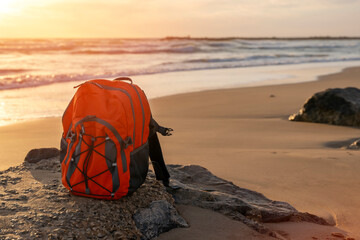 Orange rucksack on the seaside against the sea in fantastic weather. Travel insurance concept. Travel light