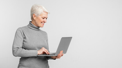 Happy mature woman typing on a laptop