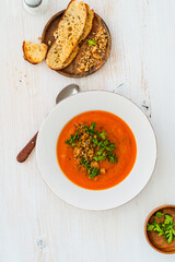 Squash soup with bread crumbs, parsley served with crusty bread on white wood, high angle view - 785667167