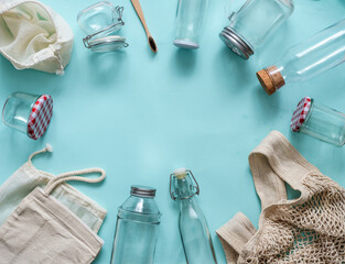 Zero waste concept. Textile eco bags, glass jars and bamboo toothbrush on blue background with copy space for text in center. Eco friendly and reuse concept. Top view or flat lay