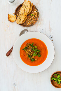 Squash soup with bread crumbs, parsley served with crusty bread on white wood, high angle view