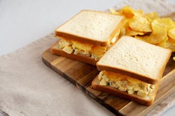 Homemade Egg Salad Sandwich with Potato Chips on a wooden board, side view. Copy space. - 785667913