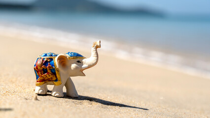 figurine of an elephant on the beach sunbathing - obrazy, fototapety, plakaty