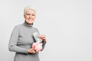Elderly woman saving in a piggy bank