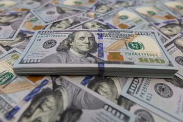 Pile of US 100 dollar banknotes on dollars background