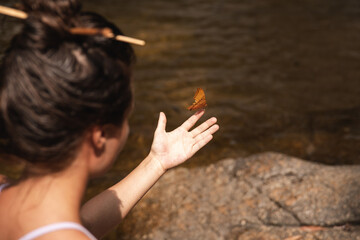 Gentle butterfly lands on the outstretched hand of a young woman