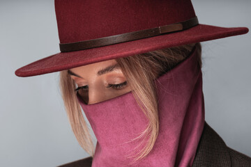 Portrait of a woman with stylish maroon hat and wild rag covering her face