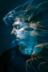Portrait of a young man with smoke in his face on dark background. Abstract motion blur effect. Lens flare.