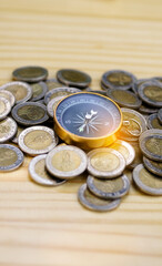 Compass and coins on wooden table background, navigation on money, guideline finance concept. Business Money Learning. Money coach.Travel saving. Cash Back from travelling. Vertical.
